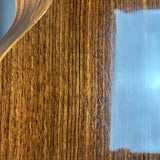 Close-up of a glossy brown wood-grain surface with a reflective blue-white patch on the right side.