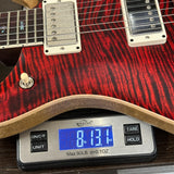 Red electric guitar on a digital scale displaying weight