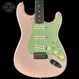 Electric guitar with a green pickguard and pink body on a black background