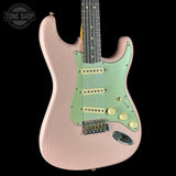 Electric guitar with a pink body and green pickguard on a black background