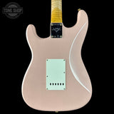 Electric guitar body with a light pink finish on a black background, featuring the Fender logo.