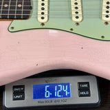 Pink electric guitar on a digital scale displaying weight.