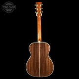 The back of a wooden acoustic guitar with a glossy mahogany-style finish, shown against a solid black background. A circular 'TONE SHOP' watermark is visible in the top-left corner.