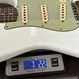 White electric guitar on a digital scale displaying weight