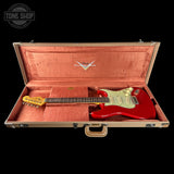 Red electric guitar in an open case with a visible brand logo on a black background.