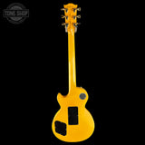 A bright yellow electric guitar shown from the back, featuring a glossy finish, black pickguard, and gold tuning pegs, set against a solid black background with a Tone Shop watermark in the top left corner.
