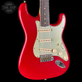 Red electric guitar with a white pickguard on a black background, featuring the Tone Shop logo.