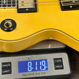 Close-up of a yellow electric guitar resting on a digital scale displaying 8.19 lbs.