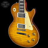A classic electric guitar with a natural flamed maple top, cream pickguard, and gold hardware, shown against a solid black background with a Tone Shop watermark in the top left corner.