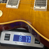 Close-up of a guitar body resting on a digital scale to show its weight, with the scale displaying 8.77 lbs.