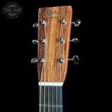 Close-up of a Martin & Co acoustic guitar headstock, showing the wood grain finish and six tuning pegs against a solid black background.