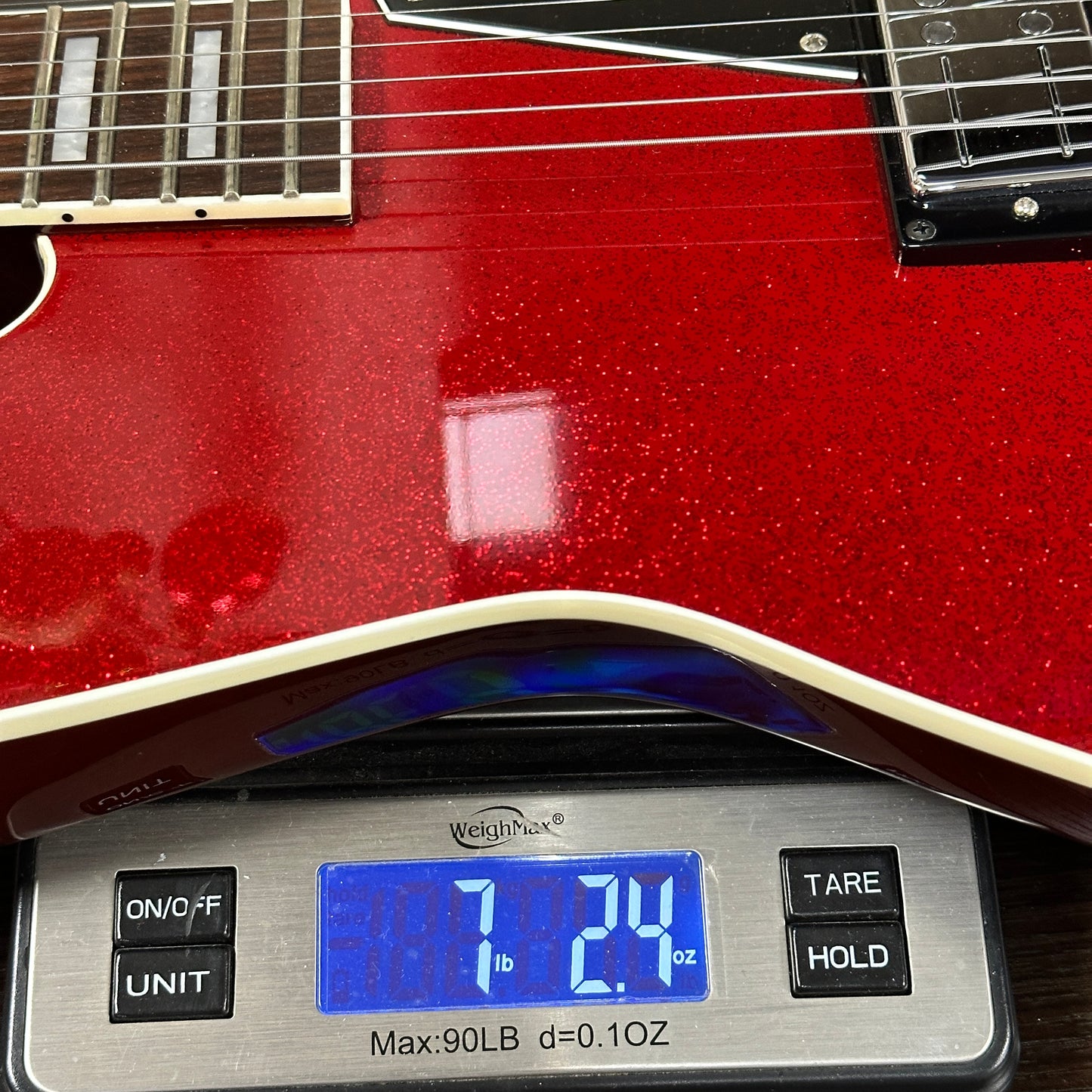 Red electric guitar on a digital scale displaying weight