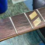 Close-up of a guitar fretboard made of dark brown wood with two light beige inlay squares on the neck.