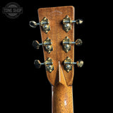 Close-up of the headstock of a guitar, showing six tuning pegs, wood grain, and a Tone Shop watermark in the top left corner.