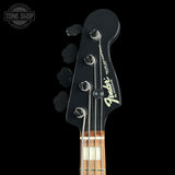 Close-up of a Fender bass guitar headstock in black with silver tuning pegs and a maple neck, shown against a black background with a Tone Shop watermark in the top left.