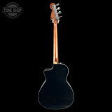The back view of an acoustic-electric guitar with a glossy black body, a natural wood neck, and silver tuning keys, shown against a solid black background with a Tone Shop watermark in the top-left corner.