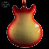 Close-up of the back of an electric guitar body with a glossy red-to-gold flame finish, shown against a black background with a Tone Shop watermark in the top left.