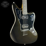 A black electric guitar with a glossy metallic black finish, a black pickguard, and chrome hardware, shown against a solid black background with a Tone Shop watermark in the top left corner.
