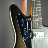 Close-up of a double-cutaway electric guitar body showing a metallic gold-flecked black finish, a dark blue pickguard with silver screws, a chrome hardware cover, and part of the fretboard.