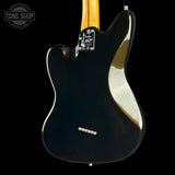 The back of a Fender Telecaster electric guitar with a glossy black body, a natural wood neck, and a chrome hardware plate, shown against a solid black background.