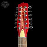 Close-up of a red Danelectro twelve-string guitar headstock with silver tuning pegs and a light wood fretboard, shown against a black background.