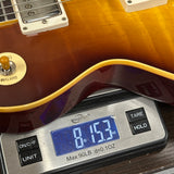 A close-up of a guitar body resting on a digital scale showing a weight of 8.153 oz.