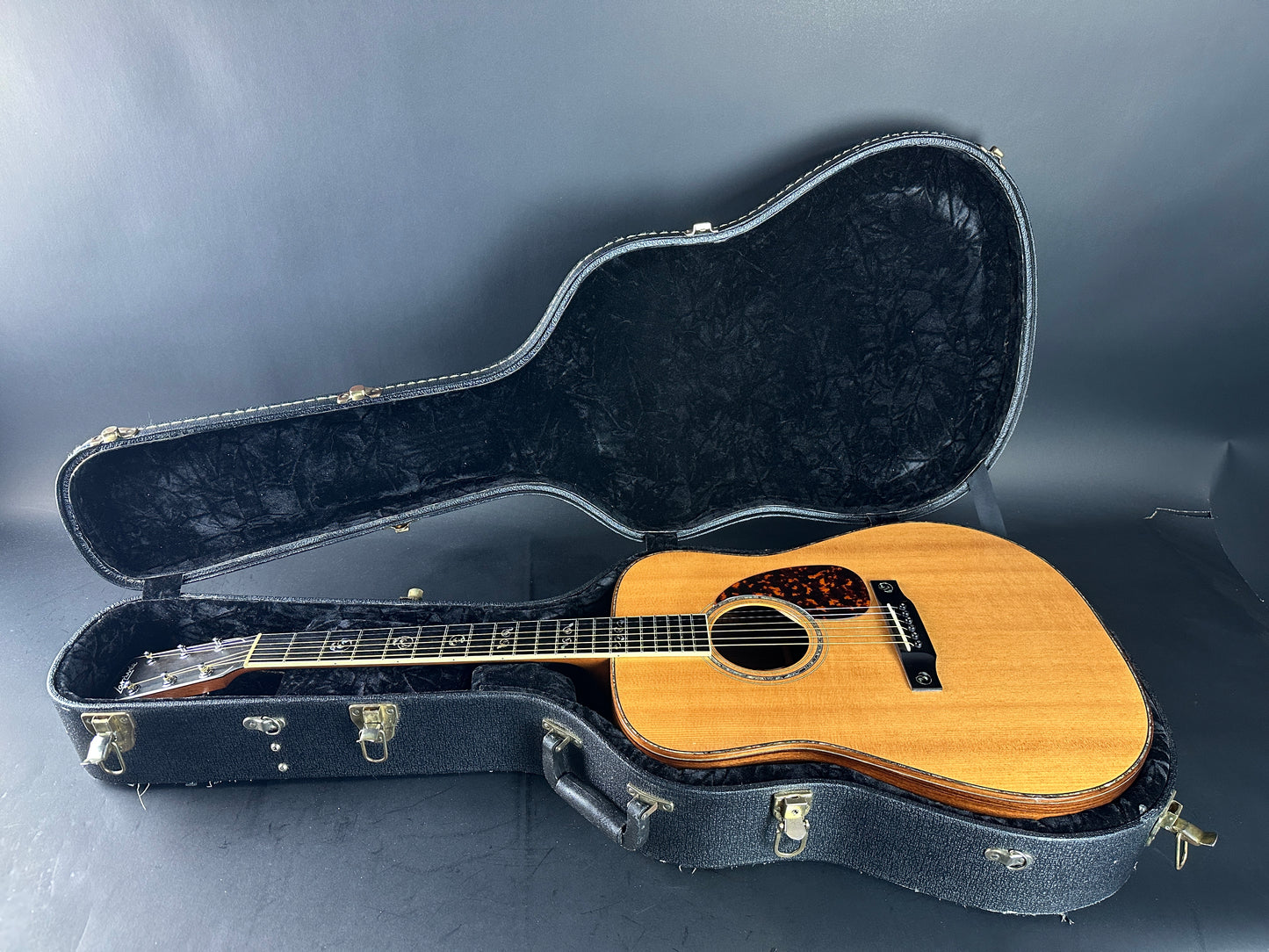 Acoustic guitar in an open black case on a gray background