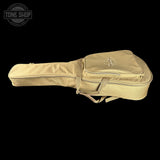 A beige nylon guitar or ukulele case with a zippered headstock end and a front storage pocket, shown against a solid black background. A Tone Shop logo is visible in the top-left corner.