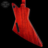 Close-up of the back of a uniquely shaped electric guitar body with a glossy dark red wood finish, shown against a solid black background. A Tone Shop watermark is visible in the top-left corner.