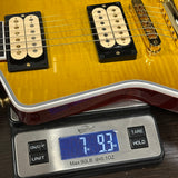 Close-up of a yellow electric guitar body resting on a digital scale showing a weight of 7.93 lbs, with the guitar pickups and part of the neck visible.