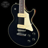 A black electric guitar with cream pickguard and humbucker pickups, shown from a three-quarters angle against a black background with a Tone Shop watermark.