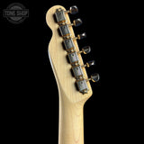 Close-up of the headstock of an electric guitar with a natural wood finish and gold-toned tuning pegs, shown against a solid black background with a Tone Shop watermark in the top left corner.