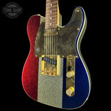 A classic electric guitar with a red, silver, and blue glitter finish, featuring a dark wood neck and gold hardware, set against a solid black background.