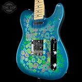 A blue electric guitar with a retro floral pattern in pink, green, and blue, shown against a black background with a Tone Shop watermark in the top left corner.