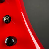 Close-up of a bright red glossy curved surface with two black knobs or switches, photographed against a dark gray background.