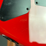 Close-up detail of a glossy red guitar body with a black pickguard and silver hardware.