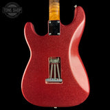 A close-up of the back of a red glitter electric guitar against a black background, showing the body, bridge, and part of the wood neck.