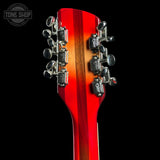 Close-up of the headstock of an electric guitar with six silver tuning pegs and a vibrant red-to-brown sunburst finish, shown against a solid black background with a Tone Shop watermark in the top left corner.
