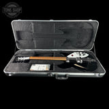 A black electric guitar with a white headstock and maple fretboard, displayed inside an open silver hard carrying case with black foam lining. The case is photographed against a solid black background, with a Tone Shop watermark in the top-left corner.