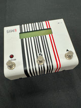 White electronic pedal with black and red stripes on a dark background