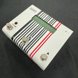 White electronic pedal with striped design on a black background