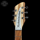 Close-up of the headstock of a Rickenroller electric guitar against a solid black background, showing the natural wood grain headstock, white brand plate, and tuning pegs.