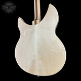The back of an electric guitar made from a single natural wood tone, showing a prominent maple grain pattern against a solid black background. A Tone Shop watermark is visible in the top-left corner.