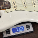 White electric guitar on a digital scale displaying weight