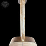 Close-up of the neck and upper body of a wooden acoustic guitar against a solid black background, showing the natural grain of the light-colored wood.
