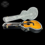 Acoustic guitar in a hard-shell case with 'Tone Shop' branding.