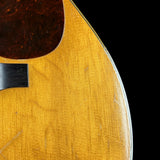 Close-up of a wooden acoustic guitar with a dark brown finish on a black background