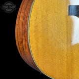 Close-up of a wooden acoustic guitar with a visible brand logo in the corner.