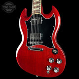 A red electric guitar with a black pickguard and chrome hardware, shown against a solid black background with a Tone Shop watermark in the top-left corner.