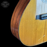 Close-up of a wooden acoustic guitar with a visible brand logo in the corner.